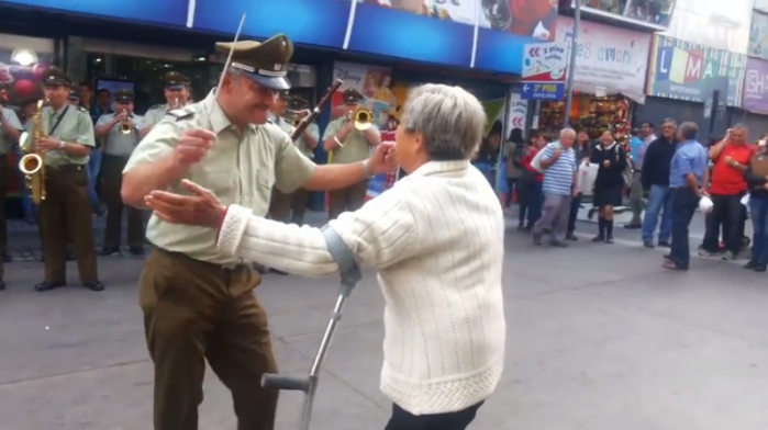 Abuelita con muleta baila cumbia con carabinero en vísperas de Navidad